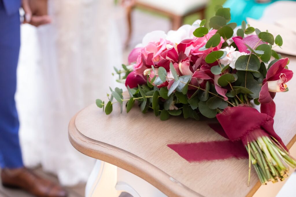 Beautiful wedding bouquet with pink roses and green foliage on a wooden table.